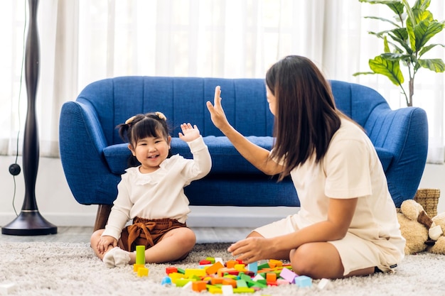 Retrato de disfrutar el amor feliz madre de familia asiática con una niña asiática sonriendo actividad aprender y entrenar el cerebro jugar con juguetes construir bloques de madera juego de educación en casa