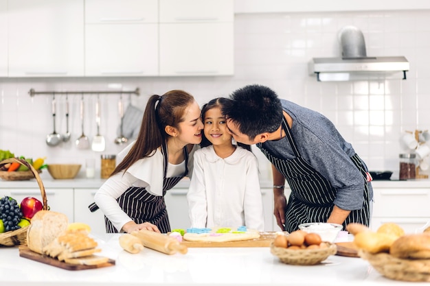 Retrato de disfrutar del amor feliz padre de familia asiática y madre con niña asiática hija niño divirtiéndose cocinando junto con hornear galletas e ingredientes de pastel en la mesa en la cocina