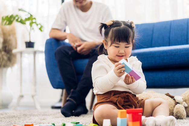 Retrato de disfrutar del amor feliz padre de familia asiático y niña asiática actividad sonriente aprender y entrenar el cerebro jugar con juguetes construir bloques de madera tablero juego educativo en casa