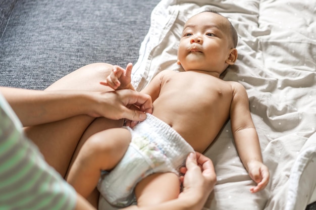 Retrato de disfrutar feliz amor familia madre asiática jugando con adorable pequeño bebé asiático Mamá tocando con lindo hijo momentos buen tiempo en un dormitorio blanco Amor por el concepto de familia