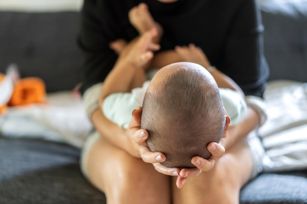 Retrato de disfrutar feliz amor familia madre asiática jugando con adorable pequeño bebé asiático Mamá tocando con lindo hijo momentos buen tiempo en un dormitorio blanco Amor por el concepto de familia