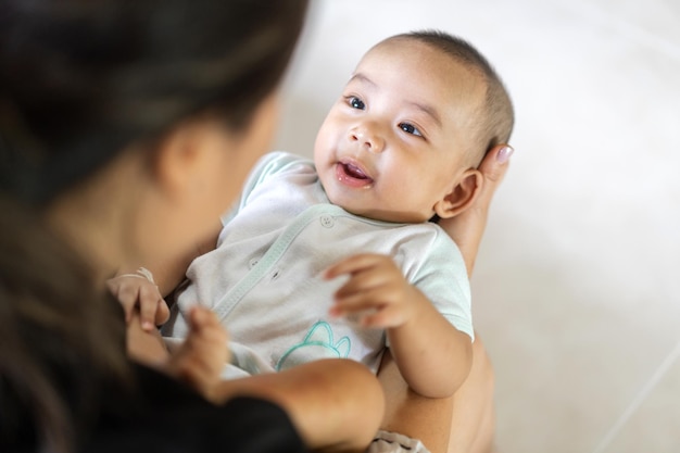 Retrato de disfrutar feliz amor familia madre asiática jugando con adorable pequeño bebé asiático Mamá tocando con lindo hijo momentos buenos momentos en un dormitorio blanco Amor del concepto de familiax9