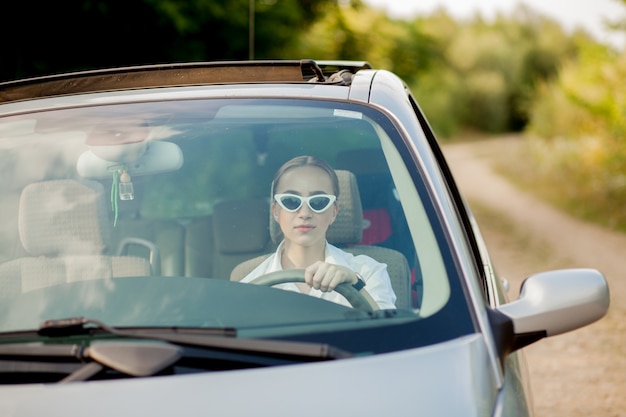 Retrato disparado através do para-brisa de uma linda mulher no carro
