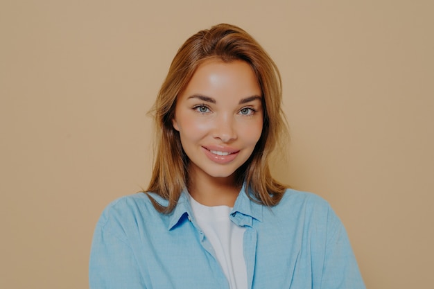 Retrato de disparo en la cabeza de mujer modelo morena feliz en camisa azul