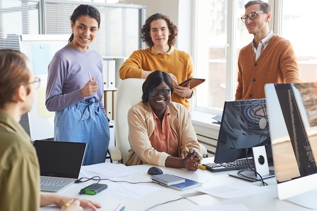 Foto retrato de diverso equipo de desarrollo de ti discutiendo el proyecto y sonriendo mientras disfruta del trabajo en el estudio de producción de software