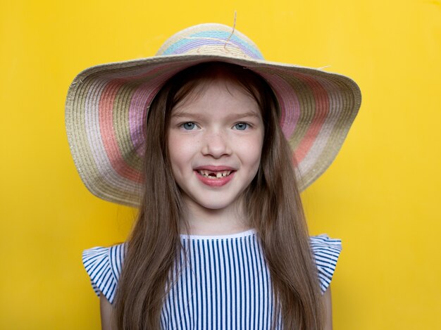 Retrato de una divertida niña desdentada en un sombrero amarillo