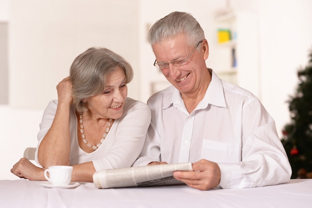 Foto retrato de la divertida pareja de ancianos leyendo el periódico