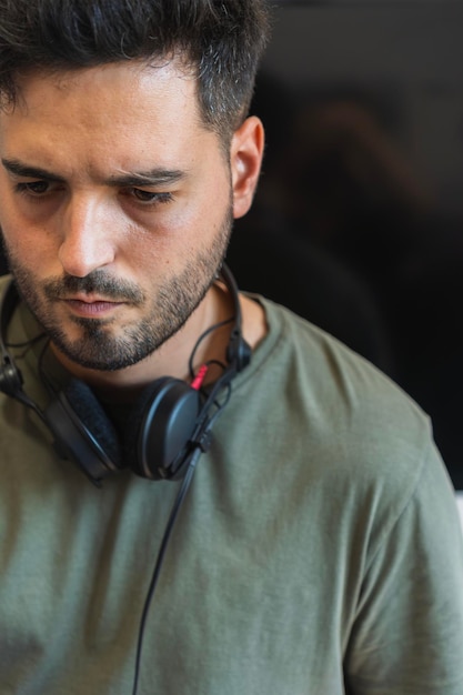 Retrato de un DJ concentrado en su estudio con los auriculares quitados