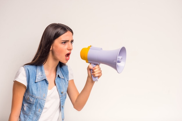 Retrato do adolescente alegre da menina, gritando em um megafone.