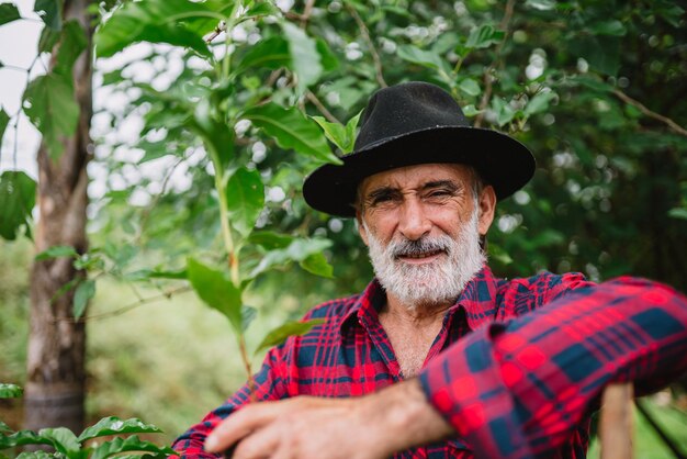 Retrato do agricultor brasileiro na camisa casual na fazenda analisando mudas de café