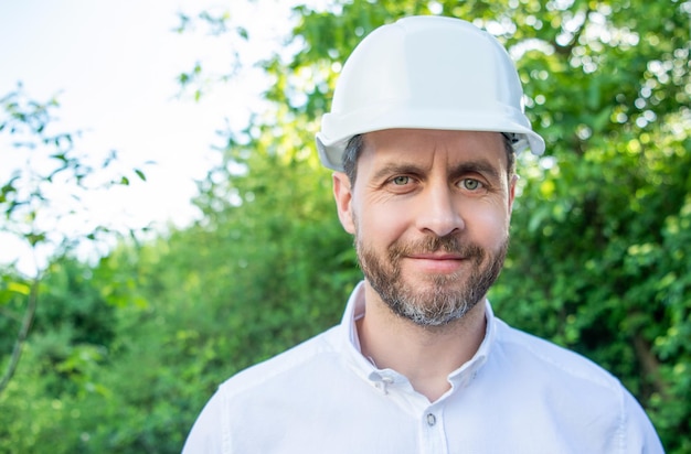 Retrato do arquiteto homem usando capacete de segurança ao ar livre espaço de cópia de fundo natural