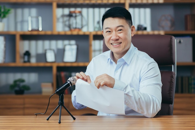 Retrato do blogueiro asiático gravando som no som do microfone de papel rasgado