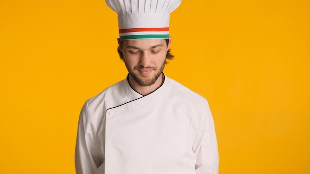 Retrato do chef masculino de uniforme em pé contra um fundo colorido Homem atraente pronto para cozinhar comida deliciosa