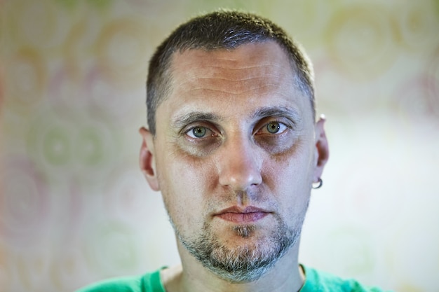 Retrato do close-up de um homem de 40 anos com sinais de fadiga, depressão ou ressaca no rosto.