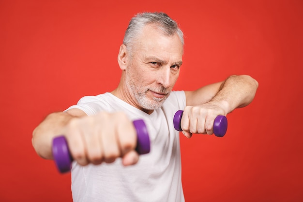 Retrato do close-up de um homem sênior que exercita com halteres.