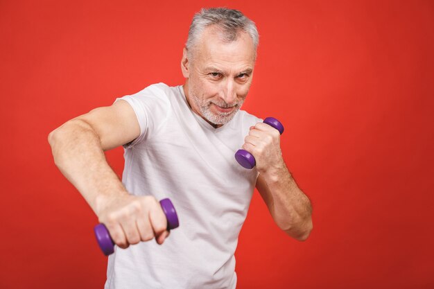 Retrato do close-up de um homem sênior que exercita com halteres.