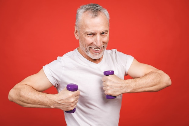 Retrato do close-up de um homem sênior que exercita com halteres.