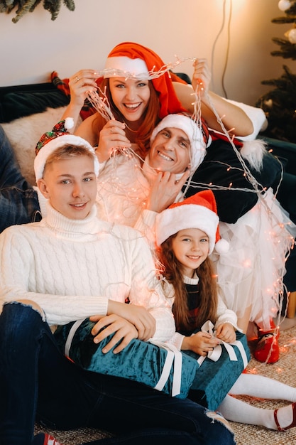 Retrato do close-up de uma família feliz sentado em um sofá perto de uma árvore de Natal, comemorando um feriado.