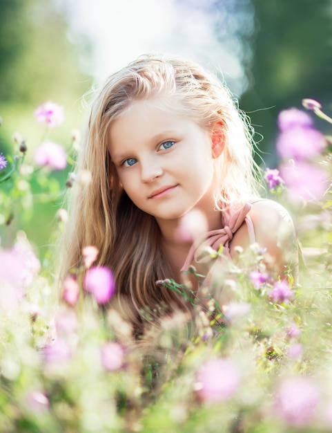 Retrato do close-up de uma menina em flores do Prado