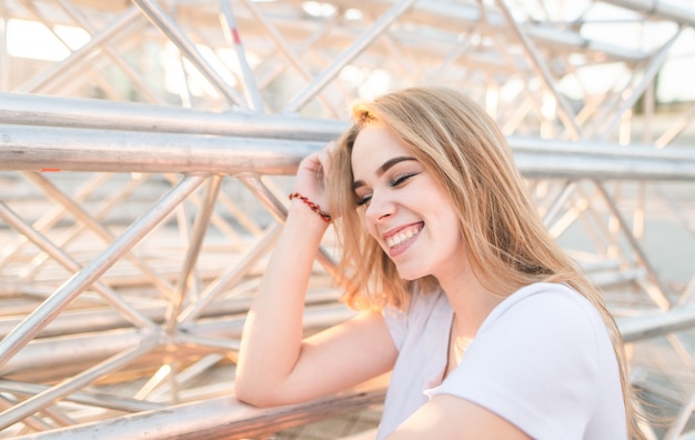 Retrato do close-up de uma menina sorridente na camisa branca com um fundo claro.