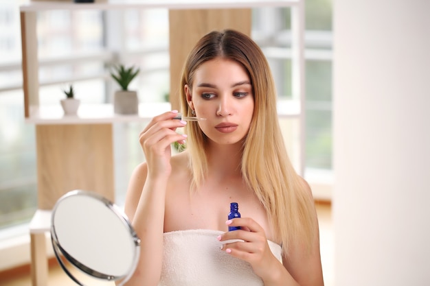 Retrato do conceito de skincare de mulher feliz, aplicando cosméticos.