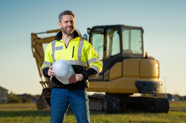 Retrato do construtor em um canteiro de obras Construtor com escavadeira pronto para construir uma nova casa Construtor de construção usa uniforme de construção em caminhão de escavação escavando construção de construtor