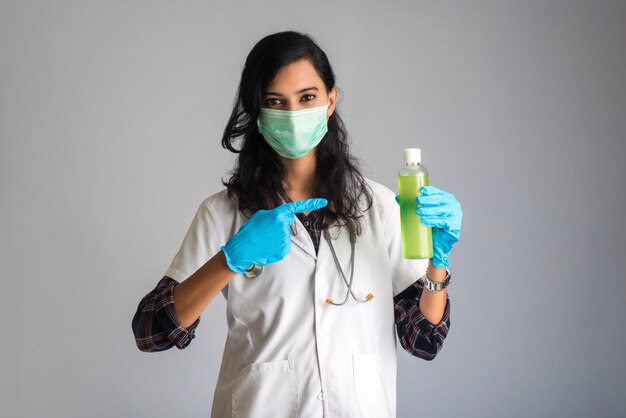 Retrato do doutor mulher mostrando um frasco de gel desinfetante para limpeza de mãos.