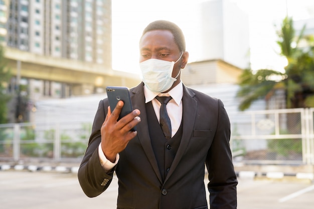 Retrato do empresário Africano com máscara usando telefone nas ruas da cidade