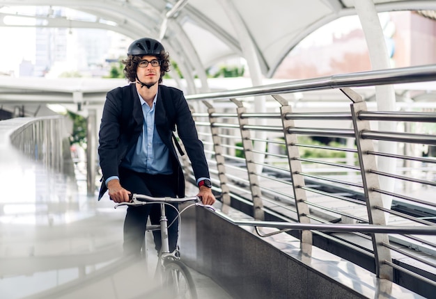 Retrato do empresário bonitão hipster de terno com mochila olhando para a frente enquanto se deslocava de bicicleta no caminho da cidade de rua para trabalhar conceito de bicicleta de transporte de viagens de negócios