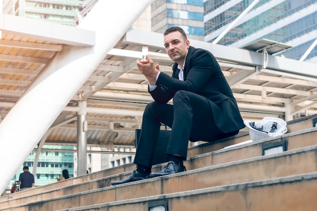 Foto retrato do empresário caucasiano bem sucedido, batendo palmas de mãos e sentado na escada.