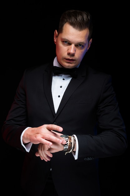 Retrato do empresário elegante elegante bonito confiante com gravata com a mão no preto no estúdio