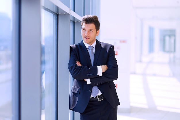 Retrato do empresário em pé perto da janela no escritório