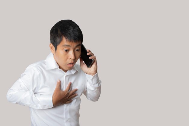 Retrato do empresário falando smartphone com gesto chocado e surpreso Cobrindo a boca com a mão Conceito de expressão de rosto de emoção humana Tiro de estúdio isolado no espaço de cópia de fundo cinza