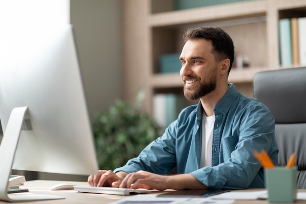 Foto retrato do empresário milenar sorridente trabalhando no computador no escritório