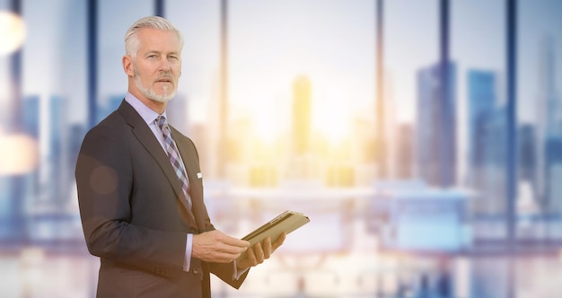 Retrato do empresário sênior na frente de seu escritório moderno com reflexos solares