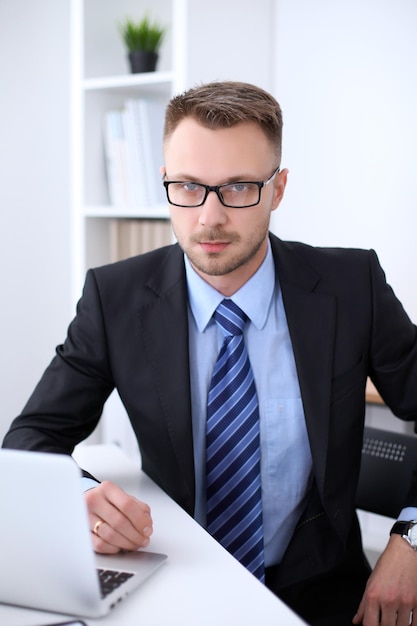 Retrato do empresário sentado à mesa no local de trabalho do escritório.