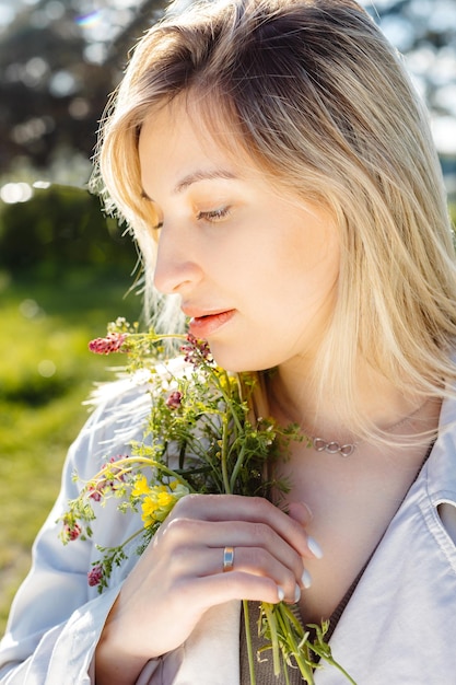 Retrato do estilo de vida da primavera de uma bela jovem sorrindo e segurando buquê de flores silvestres Conceito de felicidade e amor