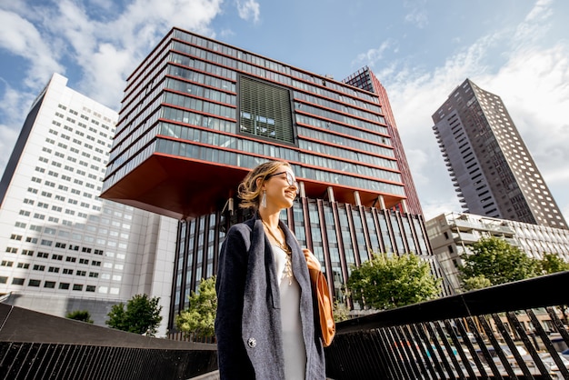 Foto retrato do estilo de vida de uma jovem caminhando na ponte em um bairro moderno com slyscrapers na cidade de rotterdam