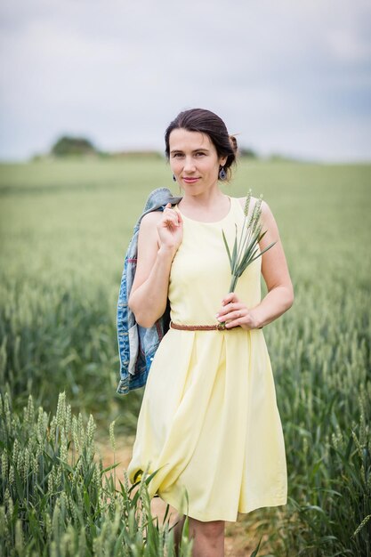 Retrato do estilo de vida de uma jovem elegante andando pelo campo de trigo