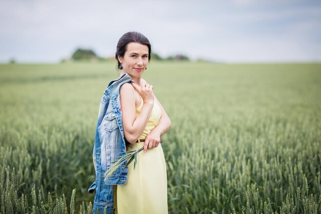Retrato do estilo de vida de uma jovem elegante andando pelo campo de trigo