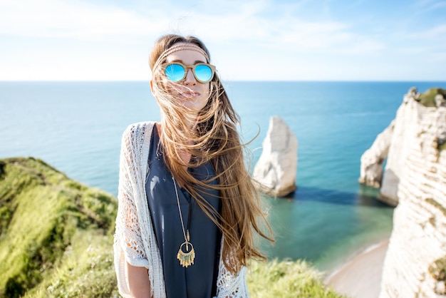 Retrato do estilo de vida de uma jovem vestida em estilo hippie, curtindo a natureza na costa rochosa com uma bela vista para o oceano na França