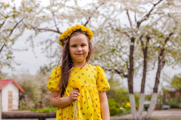 Retrato do estilo de vida de uma linda garota em um vestido amarelo e uma coroa de flores amarelas nela ...