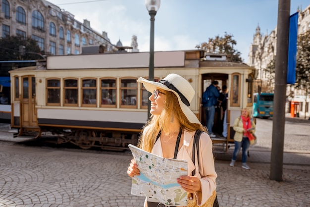 Retrato do estilo de vida de uma mulher com mapa de papel perto do famoso bonde turístico antigo na rua da cidade do Porto, Portugal