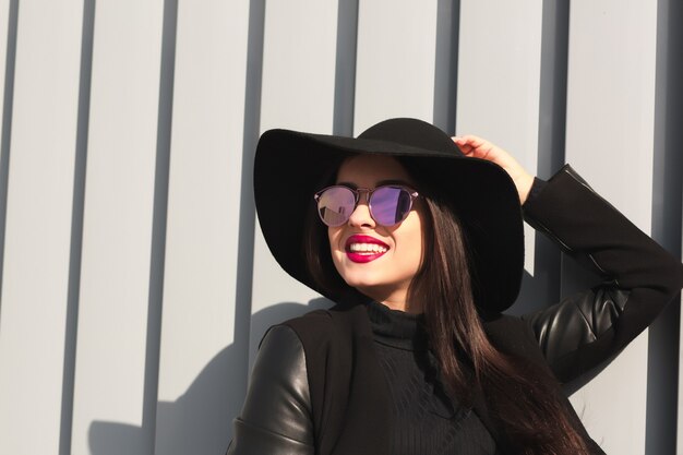 Retrato do estilo de vida de uma mulher morena feliz com maquiagem brilhante e cabelo brilhante posando sob a luz do sol