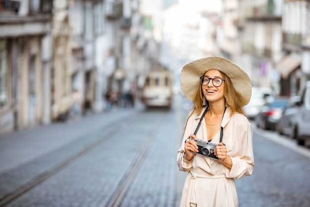 Retrato do estilo de vida de uma mulher viajante em pé na rua com o famoso bonde turístico antigo ao fundo na cidade do Porto, Portugal