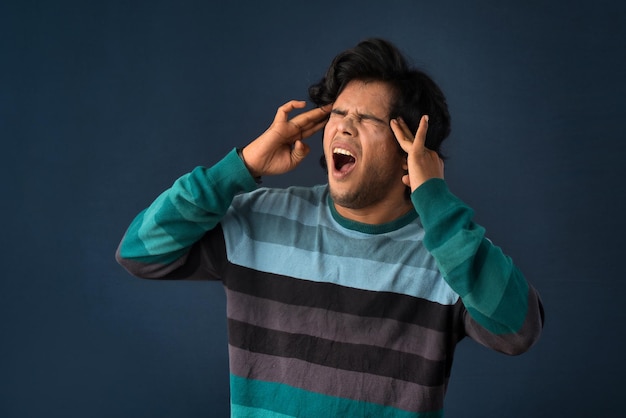 Retrato do estresse do jovem ou tendo a dor de uma dor de cabeça em um fundo cinza