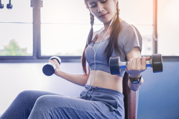 Retrato do exercício muscular do halterofilista da mulher do ajuste com pesos no gym da aptidão.