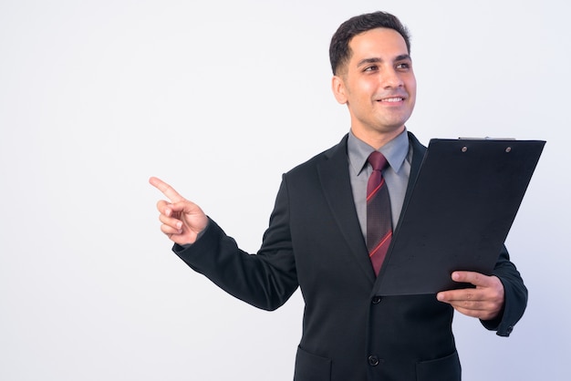 Retrato do feliz empresário persa de terno apontando o dedo enquanto segura a prancheta