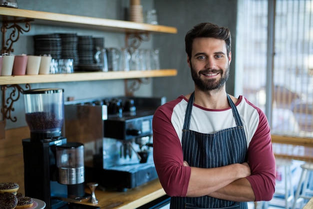 Retrato do garçom sorridente em pé com os braços cruzados