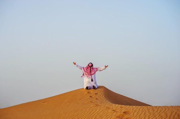 Retrato do homem árabe com sede no meio do deserto amarelo.